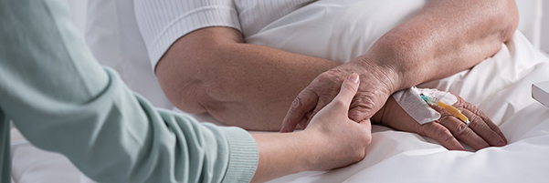 Close up of young woman consoling senior person and holding their hand