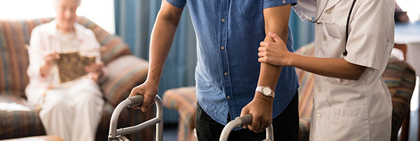 Carer helping senior man with walker aid