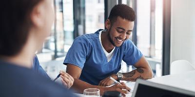 Young male carer smiling writing down notes during meeting