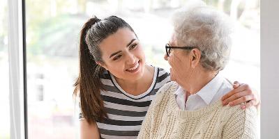 Smiling woman carer with hand on shoulder of elder woman