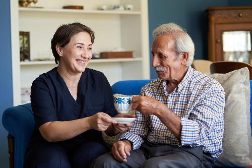 Carer offering tea to senior man