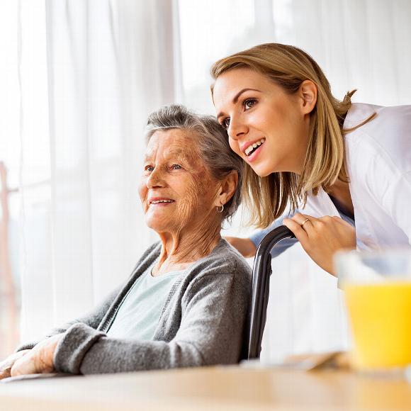 Elderly woman in wheelchair with young woman looking out window