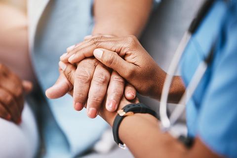 Close up of young carer holding hand consoling elder woman